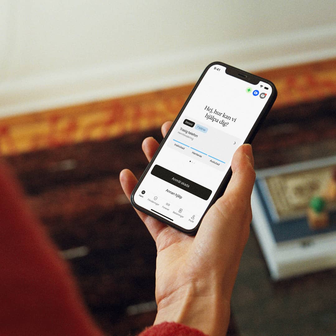 Hand håller i mobil med Hedvig-appen