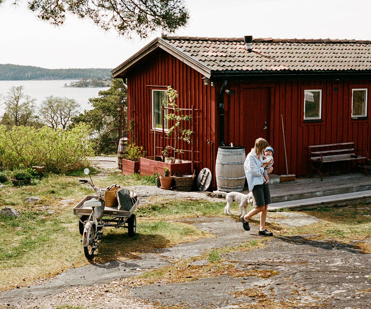 Person går med barn i famnen utanför sitt fritidshus